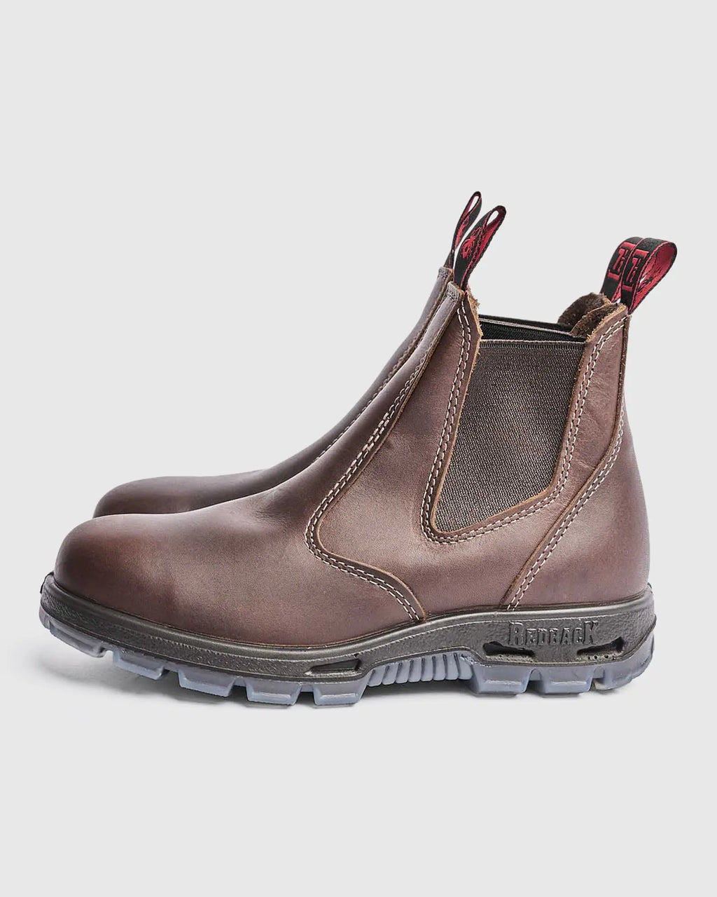 Brown leather chelsea boot with red accents on a light gray background
