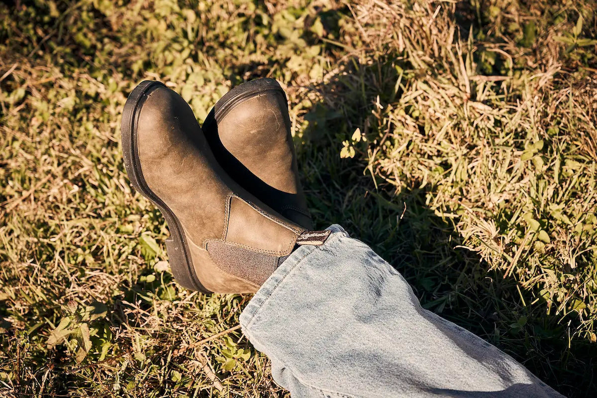 Pipeline Tan nubuck leather Whistler boots and light blue jeans on a grassy ground