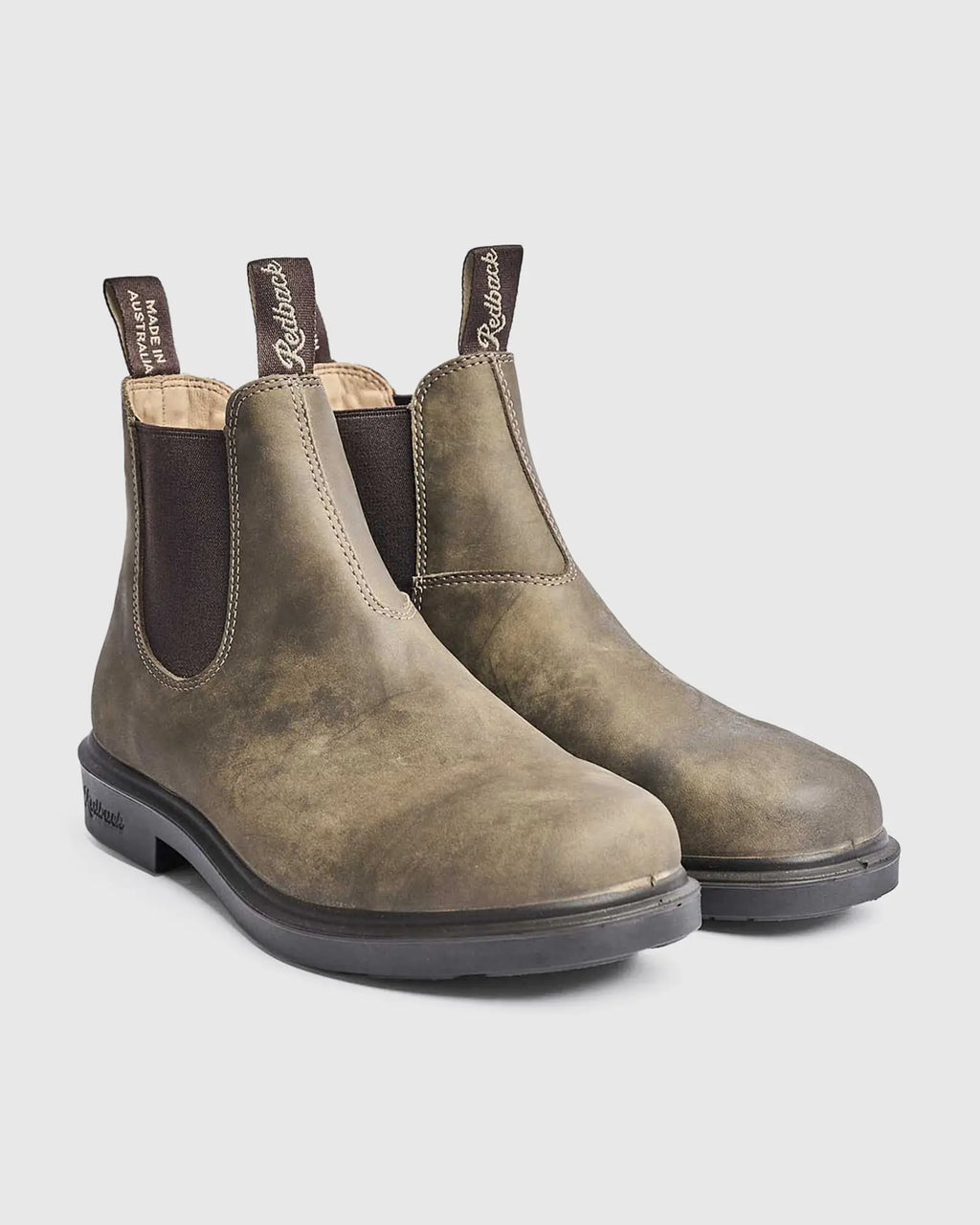 Pair of iron bark Chelsea leather boots on a light gray background