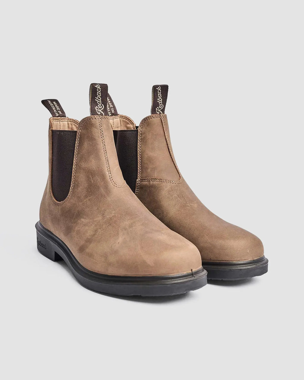 Pair of smart brown chelsea leather lifestyle boots on a light gray background