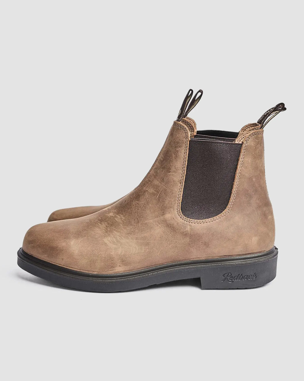 Brown leather Chelsea boots on a light gray background from the side